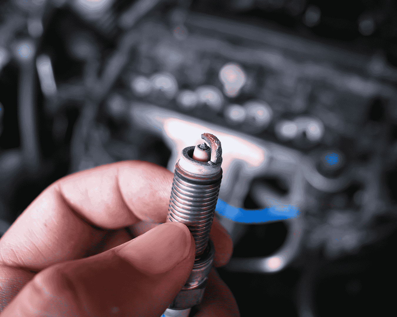 Bujía de auto sostenida por un mecánico