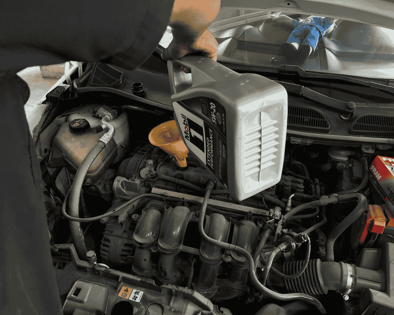 Aceite sintético premium siendo vertido en un motor durante un servicio express.