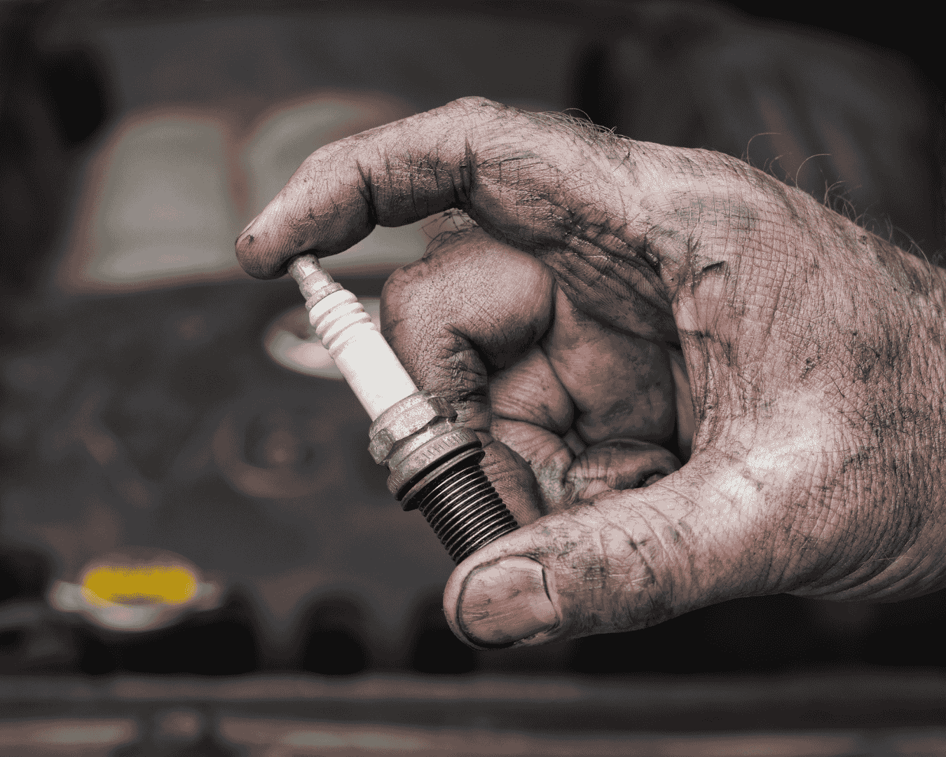 Mecánico instalando una nueva bujía de iridio en un motor.