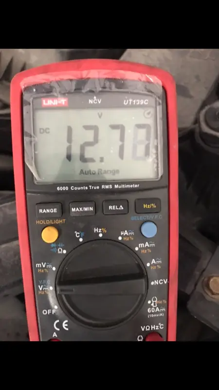 Multímetro marcando 12.77 volts