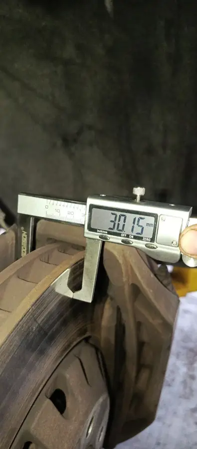 Calibrador digital midiendo el espesor de un disco de freno: 30.15 mm